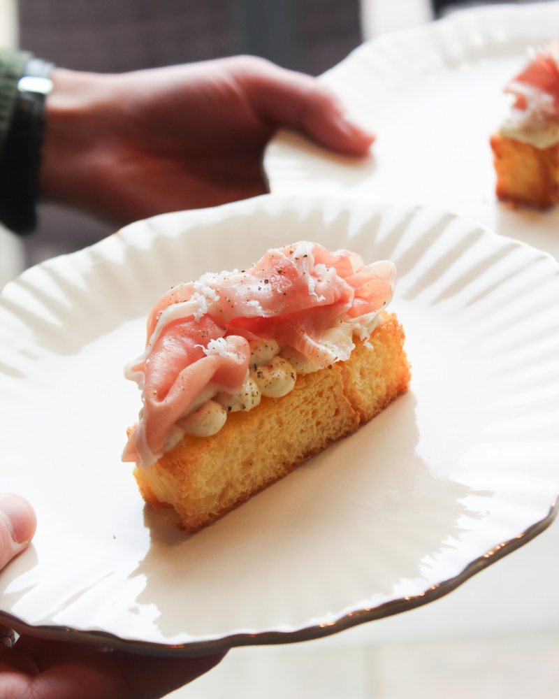 Brioche met rauwe ham en geraspte kaas op een bordje