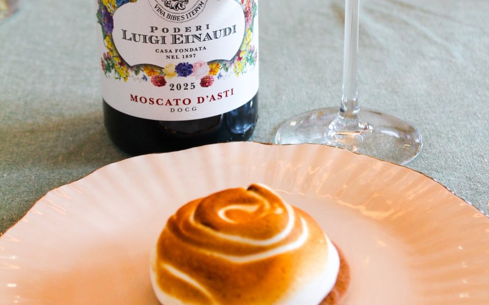 Meringuetaartje op een bordje, met een fles Moscato d'Asti en een glas erachter