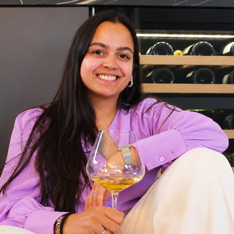 Sharin, lachend met een glas witte wijn voor haar wijnkast