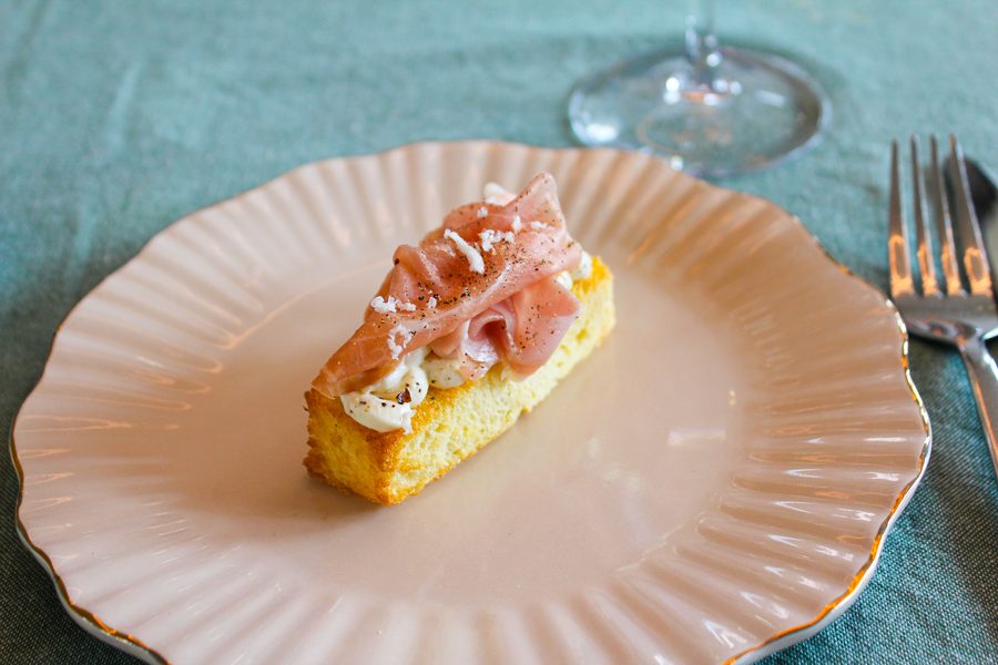 Brioche met ham op een bordje, met servet en bestek