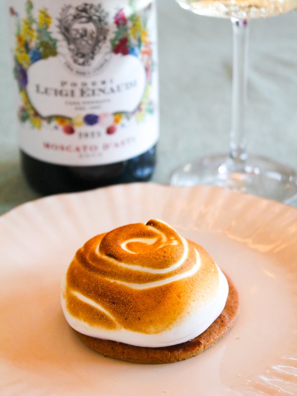 Afgebrand meringue-taartje op een bordje, met een fles Moscato d'Asti erachter